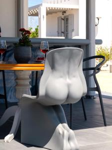 a white chair sitting next to a table with wine glasses at Sea Lilies Suites in Plaka