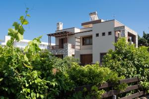 een wit huis met vegetatie ervoor bij Villa Astravi in Ialyssos