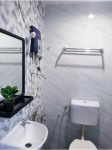 um banheiro com um vaso sanitário, uma pia e um espelho em Family Budget em Kampong Telok Sisek