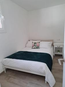 1 dormitorio con 1 cama blanca con manta verde en A Casiña do Antonio, en Nigrán