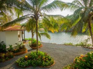 una casa junto al agua con palmeras y flores en Pont Bleu Suites, en Canacona