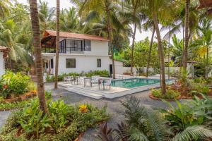 uma imagem de uma villa com piscina e palmeiras em Pont Bleu Suites em Canacona