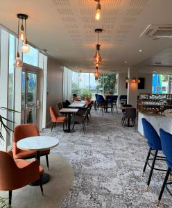 a waiting room with tables and chairs and windows at Le Mauritia Hotel et Spa in Pornic