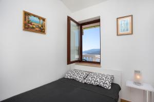 a small bedroom with a window and a bed at Greenhouse family apartments in Rabac