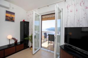 una sala de estar con una puerta corredera de cristal con vistas al océano en Greenhouse family apartments, en Rabac