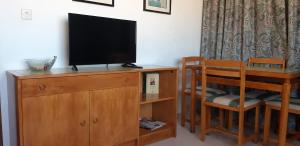 a living room with a television on a dresser with a chair and a table at Apartamento Gemelos XII -23 in Benidorm