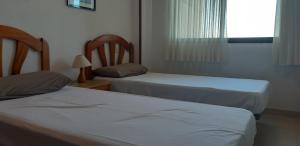 dwa łóżka w małym pokoju z oknem w obiekcie Apartamento Gemelos XII 23 IF Benidorm w mieście Benidorm +16 zdjęć