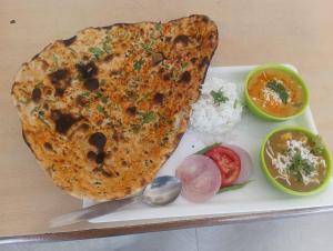 a plate of food with a piece of meat and rice at Bhandari Cottages in Dhanaulti