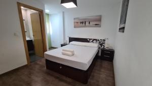 1 dormitorio con 1 cama con sábanas blancas y espejo en Apartamento Edificio Ilice -5, en Benidorm
