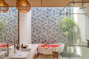 a bathroom with a tub and a glass shower at Sanora Villa Sanur by Ini Vie Hospitality in Sanur