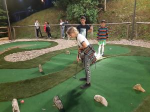 dos niños jugando al golf en un campo de minigolf en Camping la Source en Thérondels