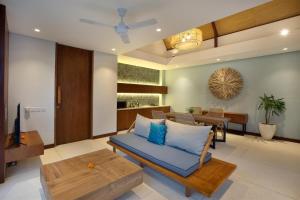 a living room with a blue couch and a table at Sanora Villa Sanur by Ini Vie Hospitality in Sanur