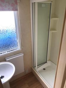 a bathroom with a shower and a sink at 6-8 berth caravan, Perran Sands Haven Holiday Park, Cornwall in Perranporth