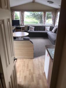 a living room with a couch and a table at 6-8 berth caravan, Perran Sands Haven Holiday Park, Cornwall in Perranporth