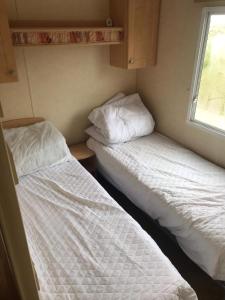 two beds in a small room with a window at 6-8 berth caravan, Perran Sands Haven Holiday Park, Cornwall in Perranporth