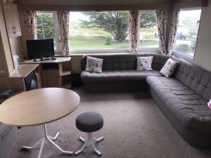a living room with a couch and a table at 6-8 berth caravan, Perran Sands Haven Holiday Park, Cornwall in Perranporth