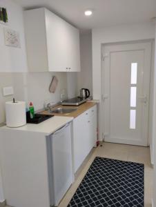 een keuken met witte kasten, een wastafel en een deur bij MARIJA APARTMAN in Osijek