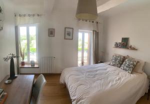 a bedroom with a bed and a desk and windows at YOGAILO maison de charme in Colombiers