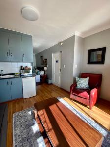 a living room with a red chair and a kitchen at 3ColoursBlue Guest House in Mossel Bay