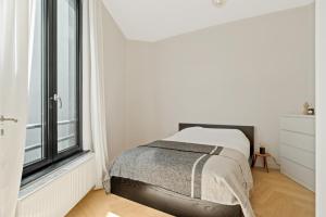 ein weißes Schlafzimmer mit einem Bett und einem Fenster in der Unterkunft Zuid's Charming Gem Apt in Antwerpen