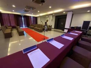 uma sala com mesas e cadeiras roxas e um homem num microfone em Hotel De Leon em Lahad Datu
