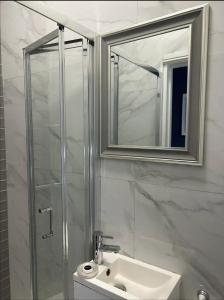 a bathroom with a shower and a sink and a mirror at Gorgeous split level Belsize Park Apartment in London