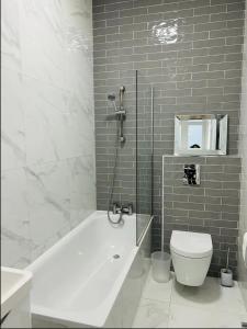 a bathroom with a white tub and a toilet at Gorgeous split level Belsize Park Apartment in London