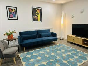 a living room with a blue couch and a tv at Gorgeous split level Belsize Park Apartment in London