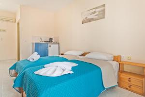 two beds in a room with blue sheets and towels at Venetia Studios in Karpathos
