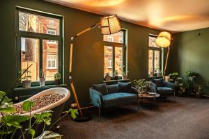 a living room with two chairs and a lamp and windows at MORE Hotel in Liepāja