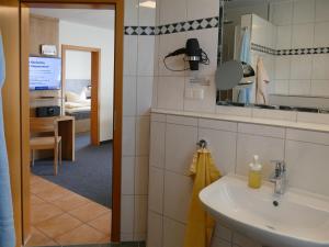 a bathroom with a sink and a mirror and a bedroom at Pension Maiglöckchen in Ostseebad Karlshagen