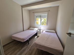dwa łóżka w małym pokoju z oknem w obiekcie Apartamento Maysan IF Benidorm w mieście Benidorm