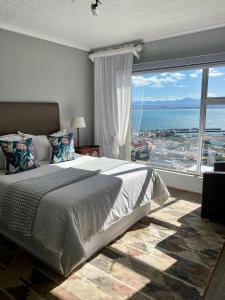 a bedroom with a large bed and a large window at 3ColoursBlue Guest House in Mossel Bay