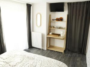 um quarto com uma cama, uma televisão e uma janela em l'Orée du Bois em Saint-Brice