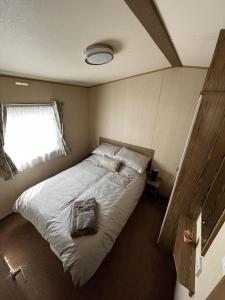 a bedroom with a bed with a pillow and a window at Whitstable, CW18, 2 bed park home, Alberta Holiday Park in Seasalter