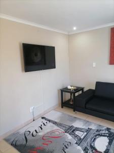 a living room with a black couch and a rug at Serenity Guest House in Soweto