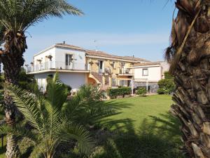 a large white house with a yard with palm trees at Torre Archirafi Resort in Riposto