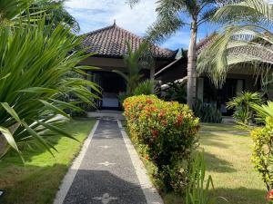 a walkway leading to a house with flowers at Kaien Villas Gili Air in Gili Air