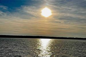 a sun setting over a large body of water at Ammersee Bungalow Verstecktes Juwel in Seenähe in Utting am Ammersee +3 photos