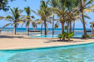 Lily Palm Resort في واتامو: مسبح مع نخل على الشاطئ
