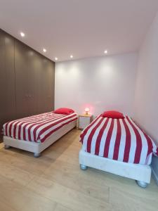2 camas con sábanas de rayas rojas y blancas en una habitación en Port Caneta Hendaye appt 55 m class 2 étoiles, en Hendaya