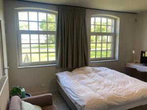 a bedroom with a white bed and two windows at Kapelhoeve in De Haan