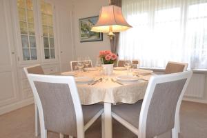 uma mesa de jantar com uma toalha de mesa branca e cadeiras em Haus-Neumann em Westerland