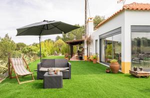 a patio with an umbrella and chairs and a lawn at Monte da Marouca-Mont’Argil in Montargil