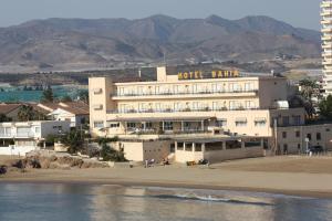 
a beach with a beach house and a large building at Hotel Bahia in Puerto de Mazarrón
