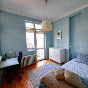 - une chambre avec des murs bleus, un bureau et un lit dans l'établissement Cozy & Stylish apartment in the heart of Sofia, à Sofia
