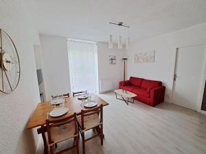 een woonkamer met een tafel en een rode bank bij Le Colibri - Appartement 4 à 6 couchages avec terrasse in Allemont