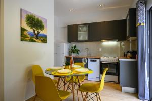 a kitchen with a table and yellow chairs in a kitchen at Chic Apartment in Nature, 5-min walk to the Beach in Kalamata