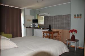 a bedroom with a white bed and a kitchen at La Source du Broly in Soumagne