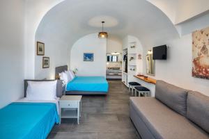 a hotel room with two beds and a couch at Kalimera Hotel in Akrotiri